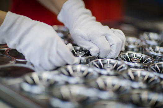 Arbeiter steckt lackierte Metallbauteile auf.JPG